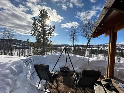 a snow covered porch with two chairs in the snow at Kinnkosen - cabin with panoramic view for 6 persons in Ål