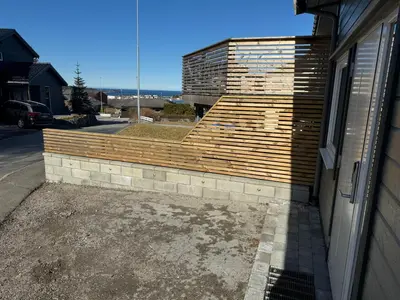 a brick retaining wall next to a house at Ekskluzywny hybel w zaciszu in Kristiansund