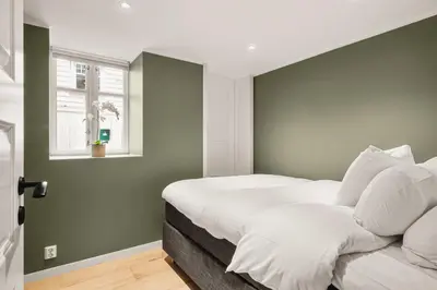 a bedroom with a bed with white sheets and a window at Bryggen Hideaway I Lux Feeling & Private Patio in Bergen