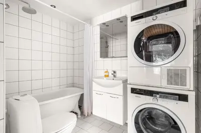 a white bathroom with a washer and dryer in it at Unique gem overlooking the world famous Bryggen in Bergen