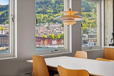 a dining room with a table and chairs and large windows at Unique gem overlooking the world famous Bryggen in Bergen