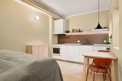a bedroom with a bed and a table and a kitchen at Fresh studio apartment, a short walk from Bryggen in Bergen