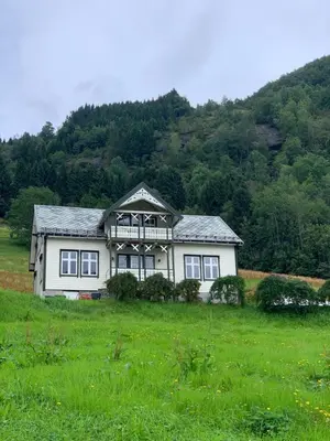 a white house in a field with a hill at Villa Flo in Stryn