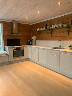 a kitchen with wooden walls and white cabinets and a sink at Villa Flo in Stryn