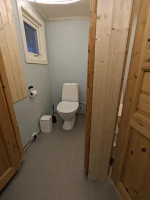 a bathroom with a toilet and a window and a door at Overnatting Rodal in Valsøybotn