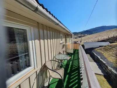 two chairs and a table on the balcony of a house at Overnatting Rodal in Valsøybotn