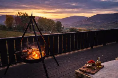 a fire grill on a deck with a table with a drink at Smie på sjarmerende og historisk gård in Baukål
