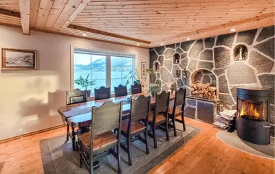 a dining room with a table and a fireplace at 4 Bedroom Awesome Home In Tørvikbygd in Tyrvikbygd