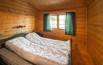 a bed in a log cabin with a window at Awesome Home In Venabygd With Sauna in Venabygd
