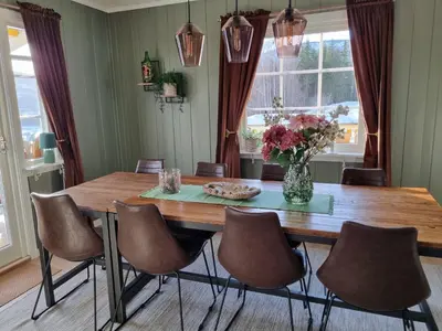 a dining room table with chairs and a vase of flowers at Solhaug in Torpo