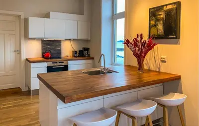 a kitchen with a sink and a counter with stools at 1 Bedroom Stunning Apartment In Ålesund in Ålesund