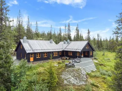 a large black house in the middle of a forest at Your Ideal Getaway Awaits in This Charming Cabin Retreat in Nord Torpa