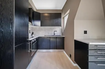 a kitchen with dark wood cabinets and a sink at Penthouse apartment in Bergen in Bergen