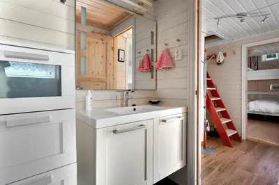 a white kitchen with a sink and a ladder at Sjötun Fjord Cabin, with boat in Stanghelle