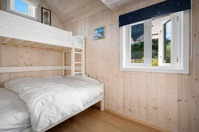 a bedroom with a bunk bed and a window at Sjötun Fjord Cabin, with boat in Stanghelle