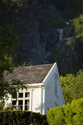 a small white house in front of a mountain at Hotel Aak in Åndalsnes