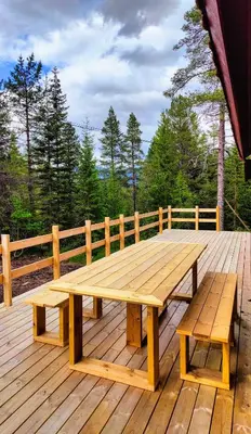 a wooden picnic table and benches on a wooden deck at Tronstadbu- 1800s Cabin near Geirangerfjord & Slogen Hike in Hellesylt