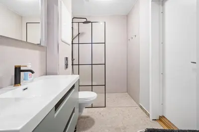a white bathroom with a toilet and a shower at Elegant Urban Apartment in Bergen