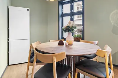 a dining room with a table and chairs and a refrigerator at Elegant Urban Apartment in Bergen