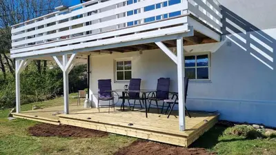 a house with a deck with chairs and a table at Leilighet på Bekkeli, Beito. in Beitostøl
