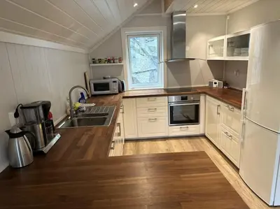 a kitchen with white appliances and a wooden floor at Rorbu i Gilsvågen - 3 soverom - Båtutleie in Austevoll