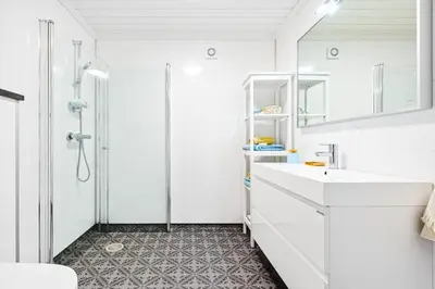 a white bathroom with a shower and a sink at Rorbu i Gilsvågen - 3 soverom - Båtutleie in Austevoll