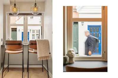 a room with a table and a man walking through a window at Bryggen // Fløyen Apartments in Bergen