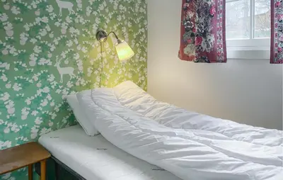 a bed in a bedroom with a lamp on the wall at 2 Bedroom Lovely Home In Innfjorden in Innfjorden