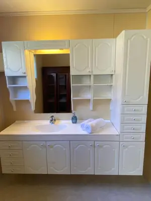 a white bathroom with a sink and a mirror at Honey bay cottage in Stadlandet