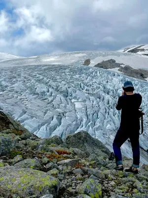 a person standing on a mountain looking at a glacier at Tungestølen in Veitastrond