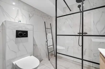 a white bathroom with a shower and a toilet at Nordnes - Amazing view of Bryggen! in Bergen