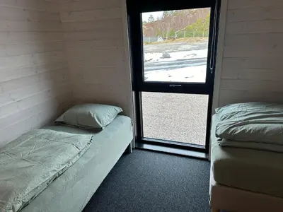 a small room with two beds and a window at Brattøya sjøstuer in Kristiansund