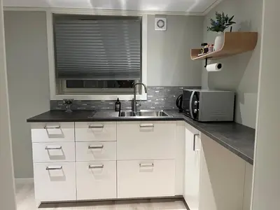 a white kitchen with a sink and a microwave at Cozy basement apartment in Orkanger in Orkanger