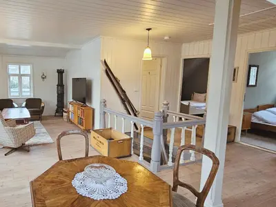 a living room with a table and a bedroom at Unikt og romslig hus perfekt for grupper in Nordfjordeid