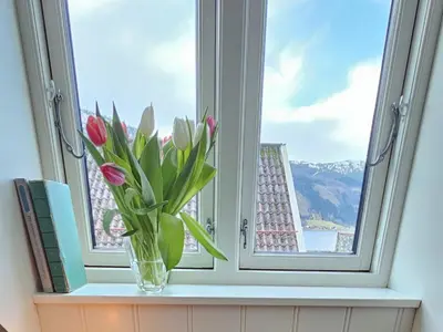 a vase of tulips sitting on a window sill with a view at Unikt og romslig hus perfekt for grupper in Nordfjordeid