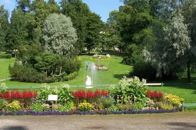 a park with a garden with flowers and a fountain at Solrikt og sentralt. Ta med både to og firbeinte in Lillehammer