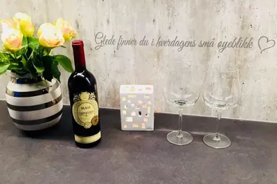 a bottle of wine and a vase with flowers and glasses at Solrikt og sentralt. Ta med både to og firbeinte in Lillehammer
