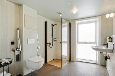 a bathroom with a shower and a toilet and a sink at Skostredet Hotel & Spa in Bergen