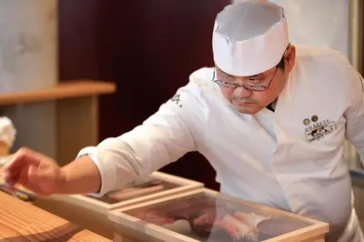 a chef is preparing food in a kitchen at Skostredet Hotel & Spa in Bergen