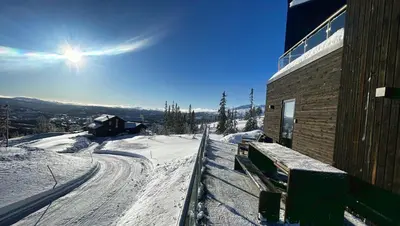 a snow covered slope next to a building on a mountain at Trilodge - Unique cabin with high standard, views, ski in & out, attractive location in Meråker