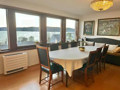 a dining room with a white table and chairs at Villa med panoramautsikt, stor uteplass og 100 m fra badestrand in Bergen