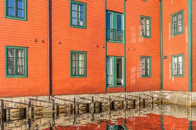 an orange building with a reflection in the water at Seaside Apt. Catch Crabs from Your Bedroom Window! in Bergen