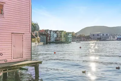 a house sitting on a dock in a body of water at Ocean-view Haven: Take a swim from your window! in Bergen