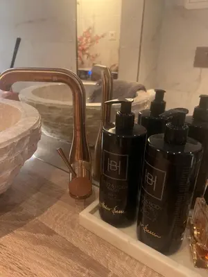 a bathroom sink with four black bottles on a shelf at Sentral leilighet i Trondheim in Trondheim