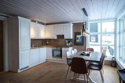 a kitchen with white cabinets and a table and chairs at Stranda Fjellgrend - with jacuzzi & 3 bedrooms in Stranda