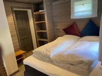 a bed with white sheets and blue and red pillows at Kvammen in Sæbø