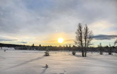 a snow covered field with the sun setting in the distance at Cozy Home In Gol With Sauna in Golsfjellet