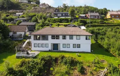 a white house on a hill with a yard at Cozy Apartment In Sveio With Kitchen in Sveio