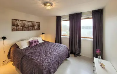 a bedroom with a bed with purple sheets and windows at Cozy Apartment In Sveio With Kitchen in Sveio
