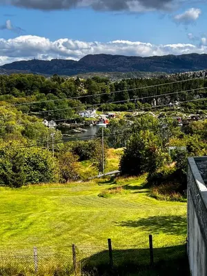 a green field with a view of a town at Fjord-View Retreat with Free Parking and Fast Internet in Nese